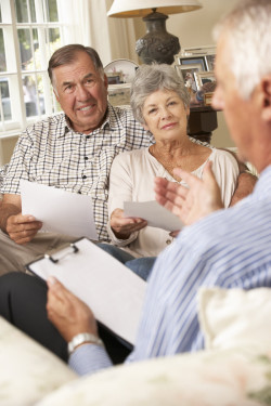 Retired Senior Couple Sitting On Sofa Talking To Financial Advisor